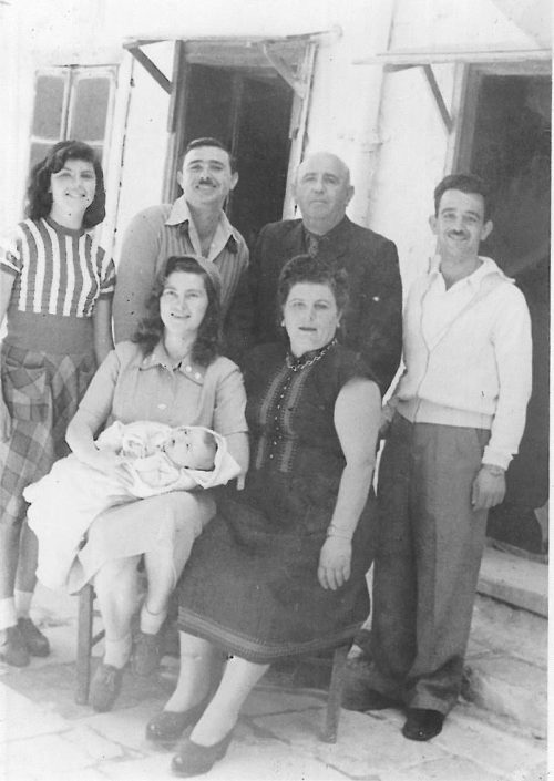 יושבות - יהודית עבו עברון ובתה התינוקת אלומה, לורה עבו, עומדים מימין לשמאל - צבי, רפאל, יוסי ועצמונה עבו
